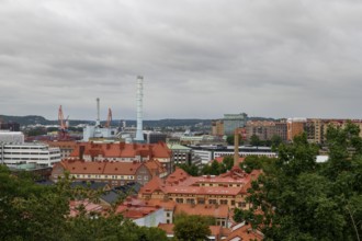 View of an urban landscape from Skansen with industrial elements and red roofs under a cloudy sky,