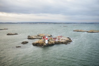Small rocky island with lighthouse and red buildings in the calm sea, near Gothenburg, Västra