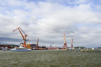 Industrial port on Götaälv in Gothenburg with several large cranes on the riverbank, Gothenburg,
