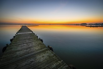 Wooden walkway leads into quiet Dümmer Lake at bright sunset, Lembruch, Dümmer See, Lower Saxony,