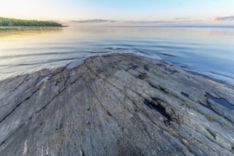 Far-reaching view of the quiet lake Vänern with gently sloping granite rocks archipelago under calm