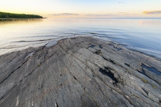 Far-reaching view of the quiet lake Vänern with gently sloping granite rocks archipelago under calm