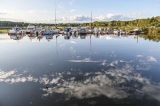 Several boats are moored in the quiet sports boat harbor of Ekenäs, water reflects the sky and the