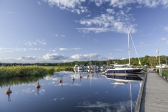 Several boats and a larger sailing yacht are moored in the quiet sports boat harbour of Ekenäs,