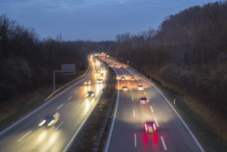 Night view of a motorway with fast moving cars and lights, surrounded by forest, near Stuttgart,