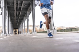 Young man running across a parisian bridge for fitness, showcasing urban training, athletic