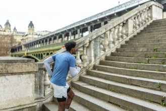 Young black man engaging in a fitness workout, actively running up historical stone stairs in paris