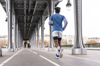 Young black man running on the bir hakeim bridge in paris, exercising in the modern urban