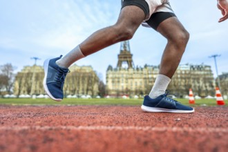 Athletic person starting a sprint on a red running track, with the iconic eiffel tower and parisian