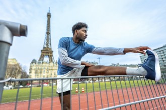 Young athletic man performing stretching exercises on a running track with the iconic eiffel tower