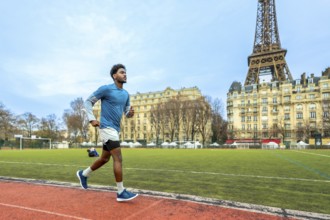 Young man training on a running track with the iconic eiffel tower and parisian buildings in the