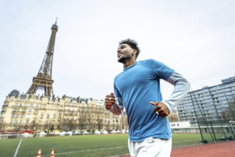 Young athletic black man training on a running track with the iconic eiffel tower and parisian