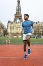 Young man doing speed drills on an outdoor running track, practicing high knees in paris with the