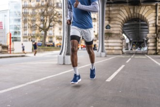 African american male athlete running on a dedicated paved track under the iconic bir hakeim bridge