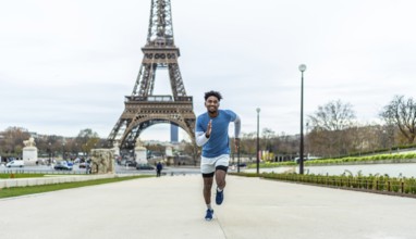 Young man actively running outdoors in front of the eiffel tower, symbolizing fitness, health, and