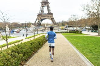 Young man exercising by running on a path in trocadero gardens, enjoying fitness and healthy