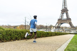 Man actively running along a path in paris, maintaining his fitness and enjoying urban sports with