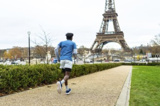 Young man exercising outdoors on a gravel path in paris, enjoying a fitness run with the iconic