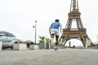 Athletic man sprinting through paris streets for urban training and fitness, eiffel tower rising