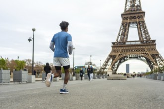 Man jogging for fitness and exercise on an urban street in paris with the iconic eiffel tower in