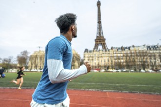 Young man training on a running track with the iconic eiffel tower and parisian buildings in the