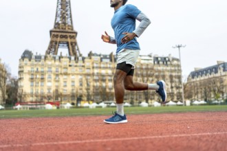 Male athlete with athletic sportswear running on an outdoor track in paris, focusing on fitness,
