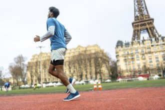 Black man engaging in physical activity, jogging for fitness and health on a tartan track in an