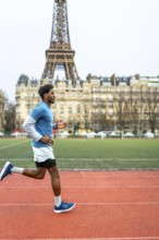 Young man running on an outdoor track in paris, training for fitness and endurance with the eiffel