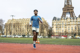 Young athletic man running on an outdoor track in paris, focusing on urban sport performance and