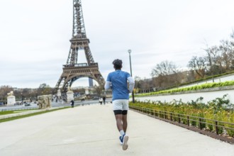 Young man in athletic wear jogging through a park pathway with the iconic eiffel tower prominently