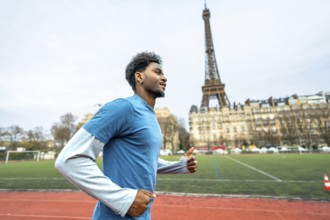 Young black man with curly hair running on a red athletic track in the city, the iconic eiffel