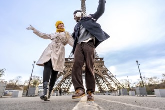 Happy diverse couple of travelers is enjoying a romantic vacation in paris, dancing with arms