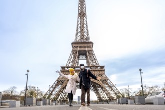 Happy young couple posing joyfully in front of the eiffel tower in paris, experiencing a romantic