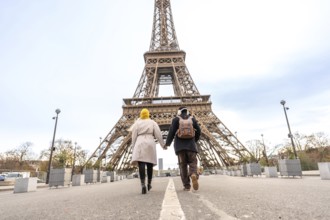 Adult male and female travelers holding hands and walking together towards the iconic landmark in