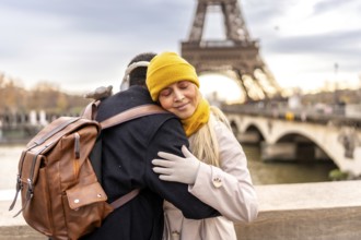 Young diverse couple embraces on a paris bridge, sharing a tender moment with the eiffel tower and
