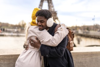 Diverse couple embracing outdoors in paris, smiling with joy and affection as they celebrate travel