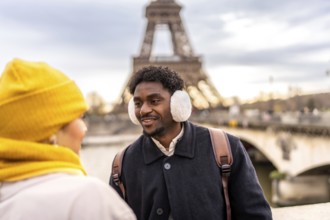 Young diverse couple interacting and smiling during their winter vacation in paris, travelers