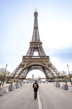 Solo traveler with backpack walks down a paris street toward the iconic eiffel tower, contemplating