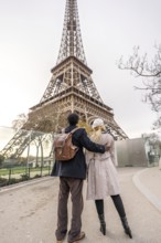Couple walking together and embracing, looking at the iconic eiffel tower, celebrating travel,