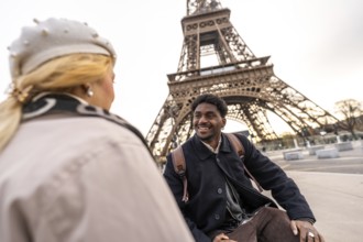 Diverse couple sharing a loving moment while travelling in paris, admiring the iconic eiffel tower