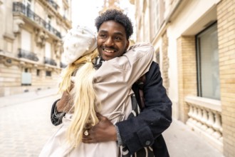 Loving diverse couple embracing and smiling on a charming parisian street, sharing a warm, romantic