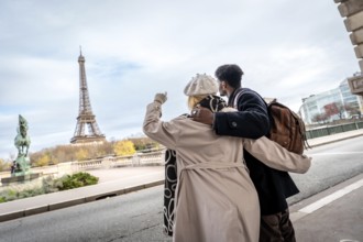 Tourists standing arm in arm along a parisian street, admiring the iconic eiffel tower in the
