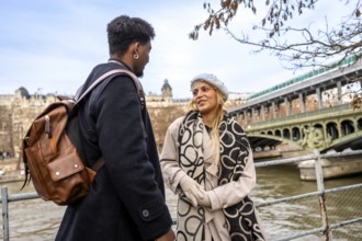 Diverse young couple chatting on bir hakeim bridge over the seine in paris, sharing a romantic