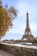 Iconic eiffel tower towering over the seine river in paris, with tour boats navigating the water