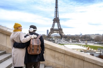 Young couple embracing on outdoor stairs with the eiffel tower in view, sharing a romantic winter