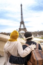 Loving couple standing with arms around each other, enjoying the view of the iconic eiffel tower in