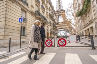 Diverse couple happily walking across a pedestrian crosswalk in a charming european street during