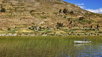 A boat on a reed lake surrounded by hills and a blue sky with clouds, the countryside and