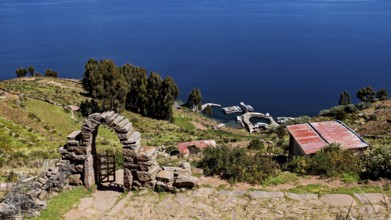 Stone archway with a view of the lake and shore. Surrounded by green hills and clear blue water,