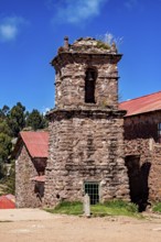 An old stone church with a bell tower and red roofs under a blue sky, The historic church on